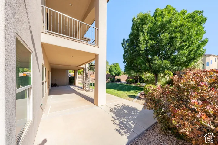 Expansive concrete patio with a covered outdoor area and an upper-level balcony featuring metal railings