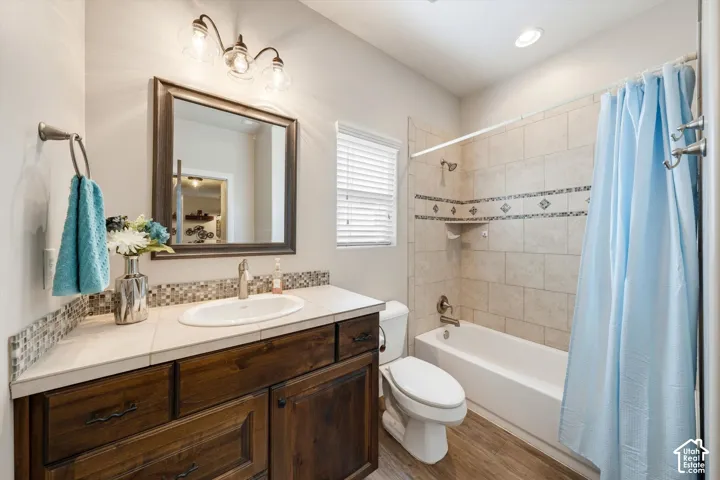 Bathroom featuring a wood-finish vanity with an integrated sink, mosaic tile backsplash, and a framed mirror
