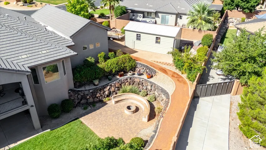 Expansive backyard featuring a paver patio with built-in seating and a fire pit, a gravel pathway, and mature landscaping