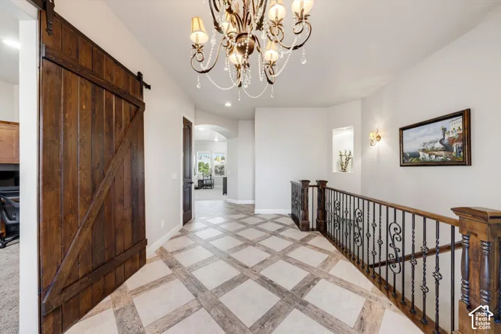 Decorative tile flooring, wood-finish barn door, chandelier, wrought iron staircase railing, and wall sconces