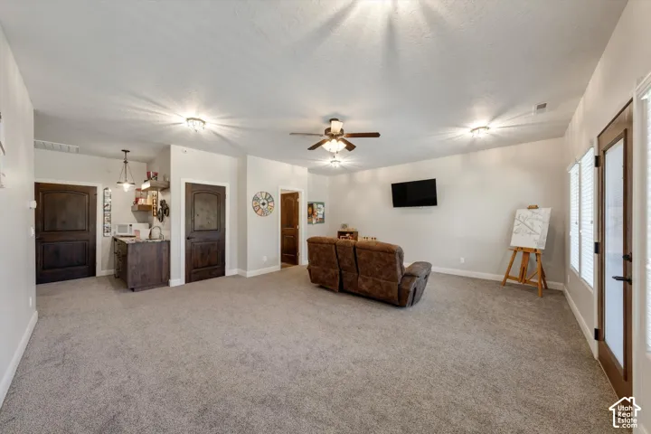 Spacious room featuring neutral carpeting, a built-in wet bar with dark wood-finish cabinetry, and multiple recessed light fixtures