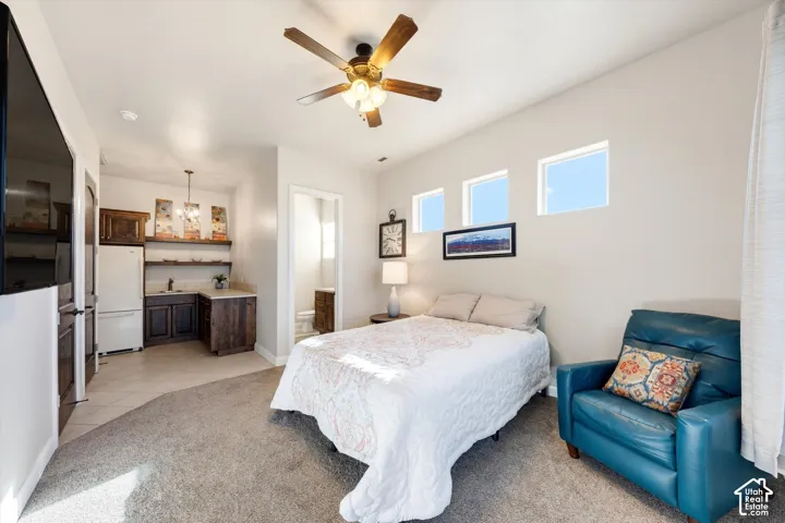 Recessed lighting, wood-finish ceiling fan, three horizontal accent windows, built-in wet bar with wood cabinetry, and a full-size refrigerator