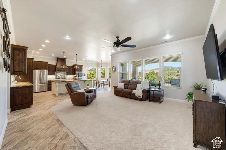 Spacious open-concept layout featuring wood-finish flooring, a kitchen island with pendant lighting, stainless steel appliances, and large windows