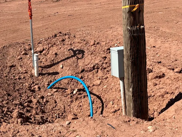 Utility pole with attached electrical box, a ground rod, and exposed conduit