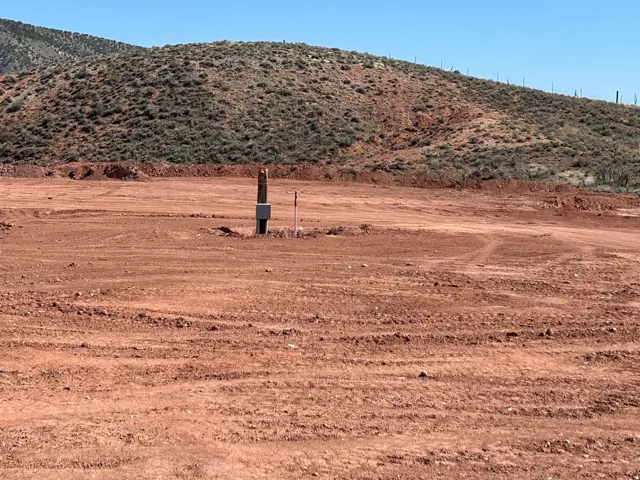 Expansive graded lot with a utility post and a natural hillside backdrop