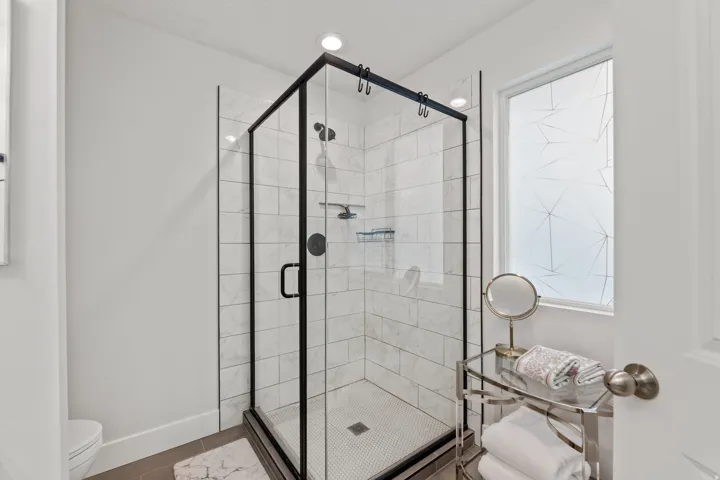 Glass-enclosed shower with black trim, subway tile surround, and a mosaic tile floor