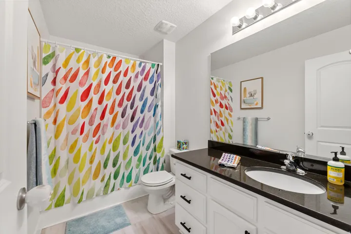 Vanity with a dark countertop, undermount sink, and chrome faucet