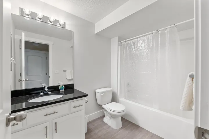 Vanity with dark countertop, undermount sink, and chrome faucet