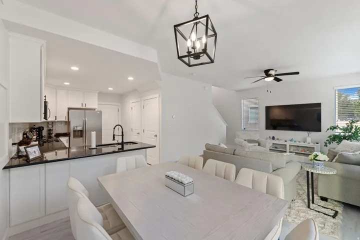 Open-concept living area featuring a kitchen with black countertops, a stainless steel refrigerator, and white cabinetry