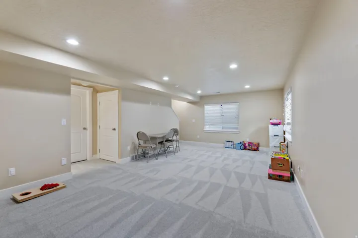 Spacious room featuring patterned carpet, recessed lighting, neutral wall tones, and two windows with blinds