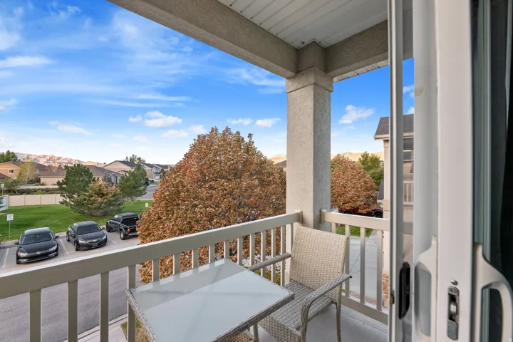 Balcony with light-colored railing, concrete flooring, and an exterior column