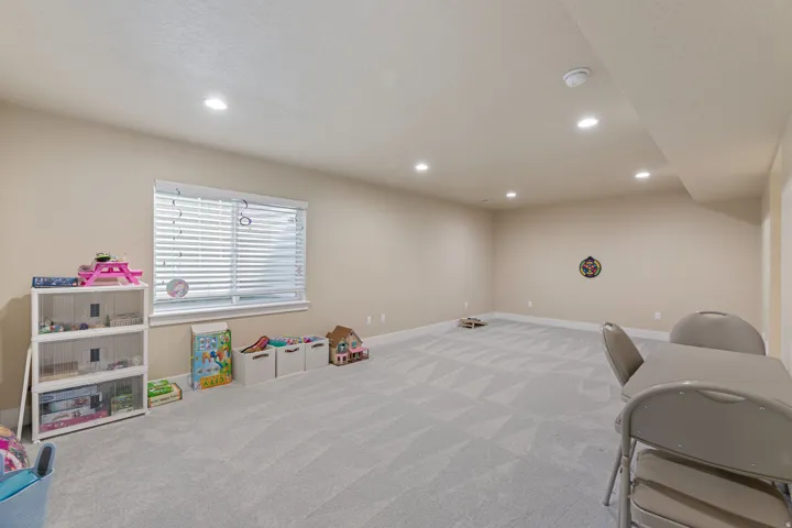 Recessed lighting, light-toned walls, patterned carpeting, and a window with blinds