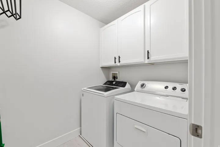 White upper cabinetry with black hardware, light wood-finish flooring