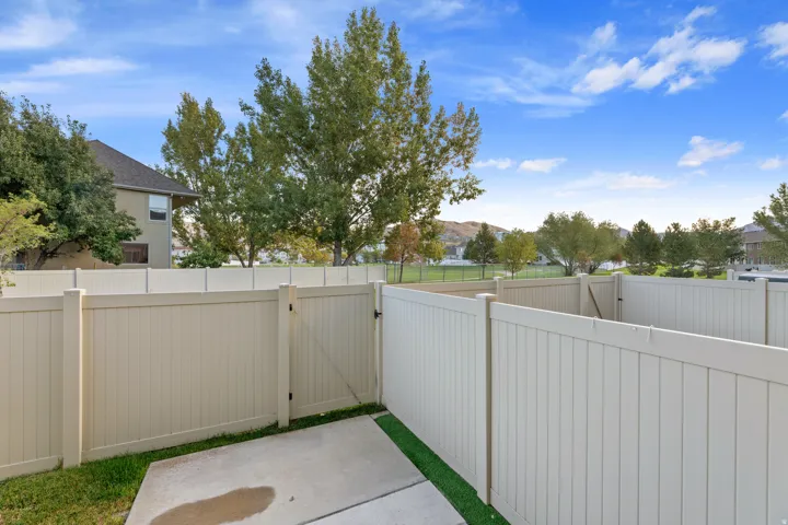 Private patio area with concrete slab, artificial turf, and full-height fencing