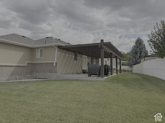 Expansive lawn area, white privacy fencing, concrete patio, and a dark wood pergola