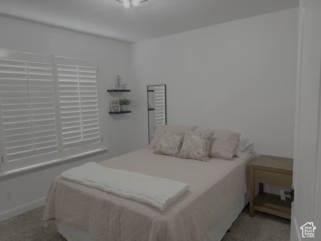 White walls with recessed window featuring plantation shutters, carpeted flooring, and a ceiling-mounted light fixture