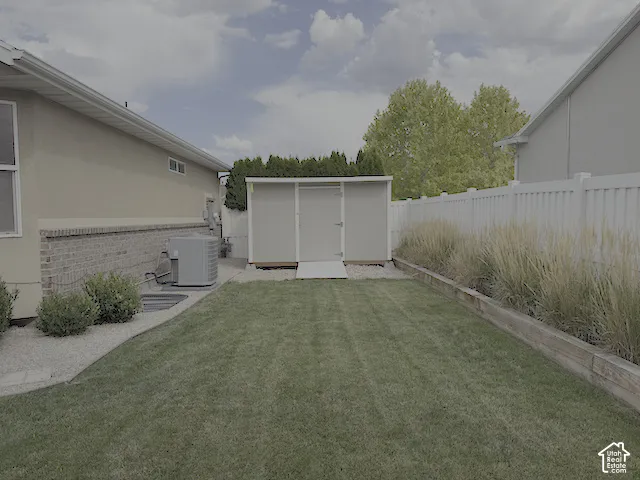 Manicured lawn with a detached shed, bordered by a white privacy fence and a landscaped rock pathway