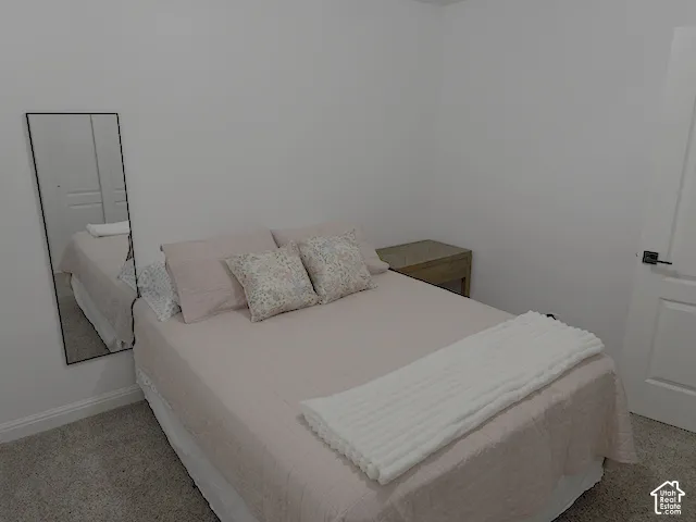Neutral wall color with a full-length mirror, wood-finish nightstand, white panel door, and dark carpet flooring