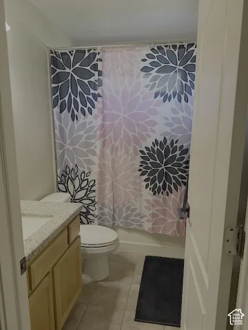 Vanity with light wood-finish cabinetry, speckled countertop, and integrated sink