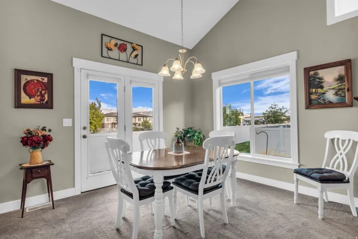 Vaulted ceiling, ceiling-mounted chandelier, double French doors, large picture window, and neutral wall color