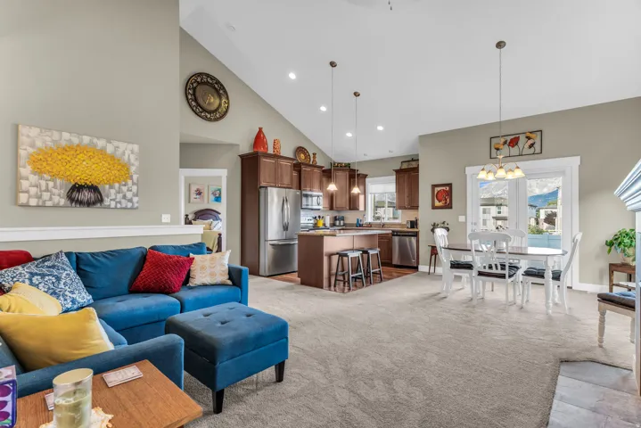 Vaulted ceilings, open concept living space, kitchen island with seating, stainless steel appliances, and a dining area with direct outdoor access