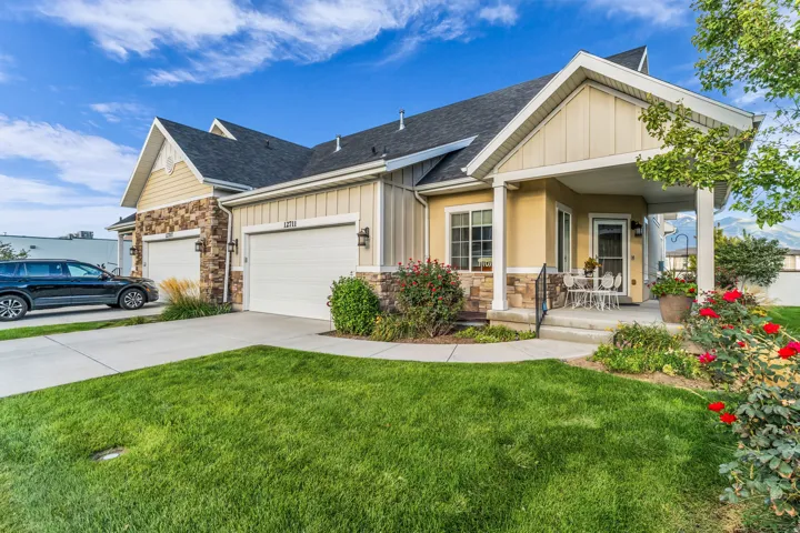 Exterior featuring a covered porch, stone accents, and a two-car garage