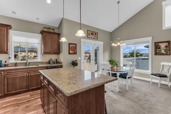 Kitchen featuring wood-finish flooring, dark wood cabinetry, a central island with a granite-style countertop, and a tile backsplash