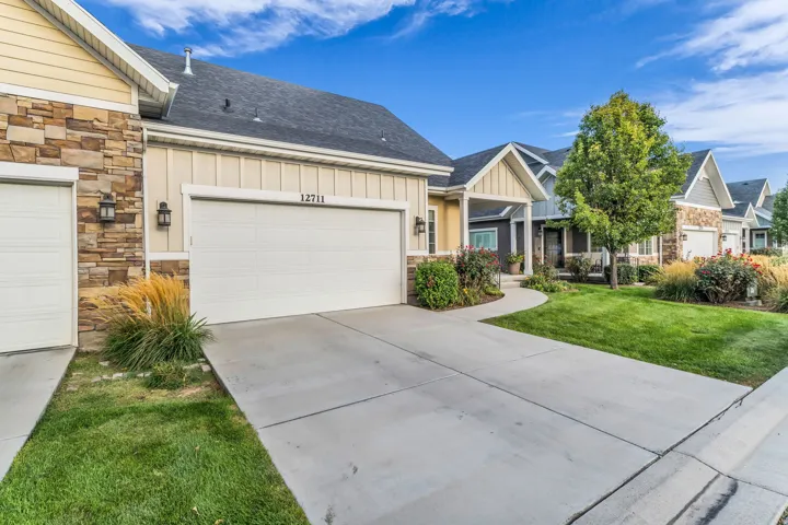 Stone and siding exterior with a concrete driveway leading to a two-car garage