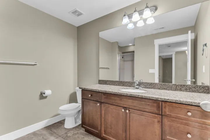 Vanity with a granite-style countertop, integrated sink, and wood-finish cabinetry
