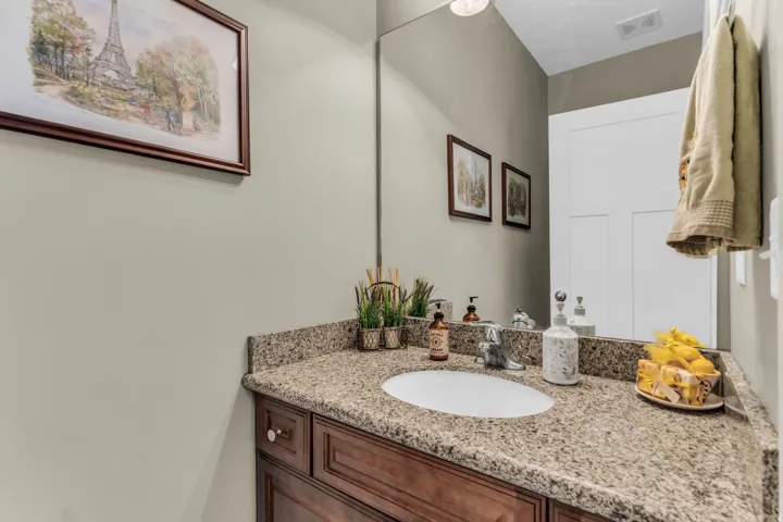 Wood-finish vanity with paneling, granite countertop, undermount sink, and chrome faucet