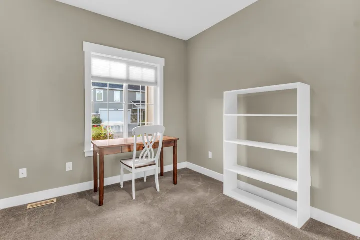 Neutral wall color, window with white trim, carpeting, built-in shelving unit