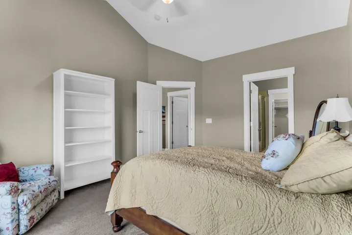 Vaulted ceiling with a ceiling fan, neutral wall tones, and white trim work
