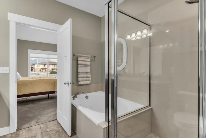 Enclosed glass shower, built-in bathtub, and a wall-mounted light fixture