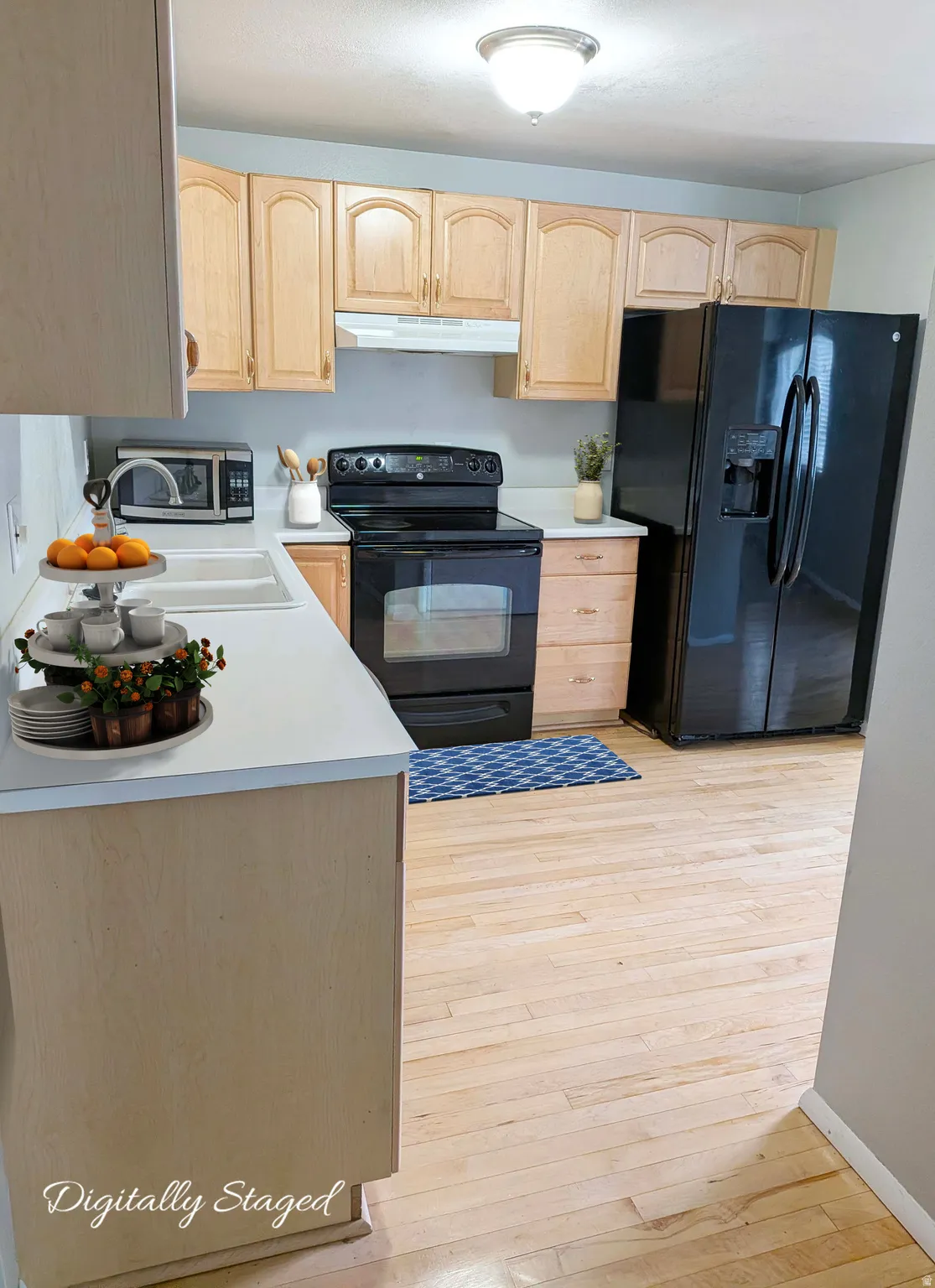Kitchen featuring light wood cabinetry, white countertops, a double-basin sink, and light wood-finish flooring
