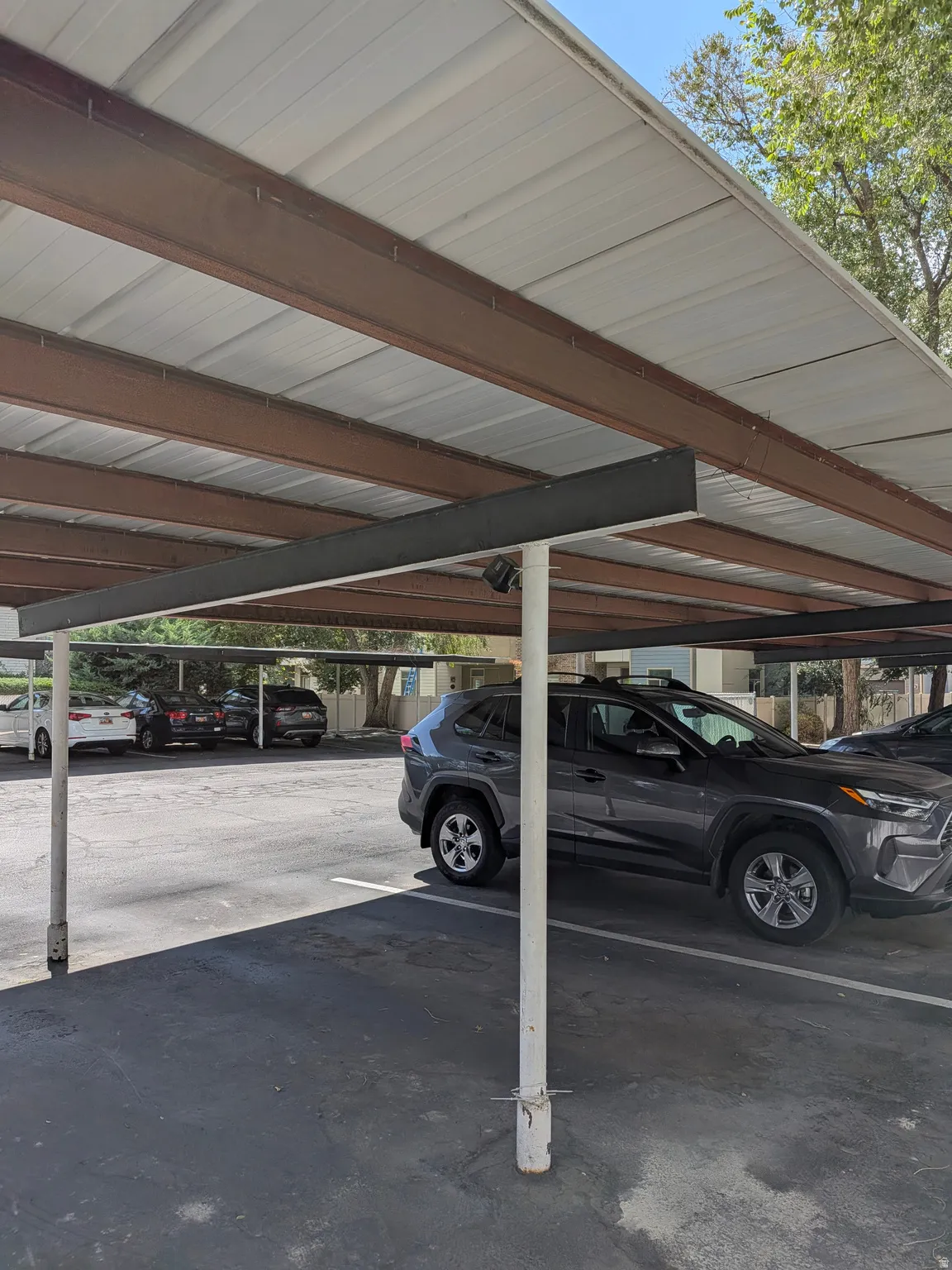 Covered parking structure with a corrugated metal roof and exposed steel beams