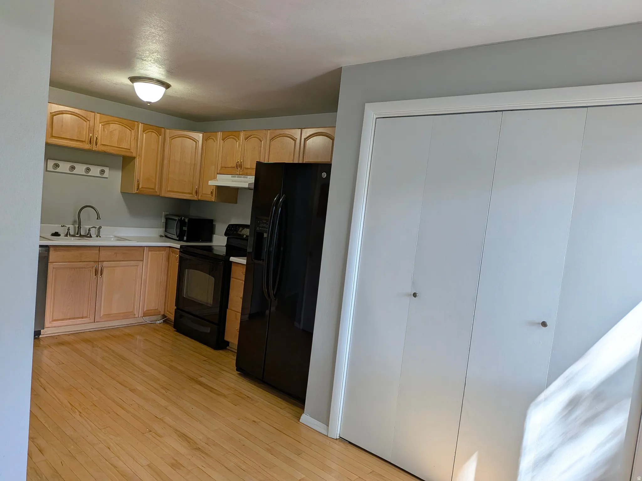 Kitchen featuring wood-finish cabinetry, white countertops, a stainless steel sink, and wood-finish flooring