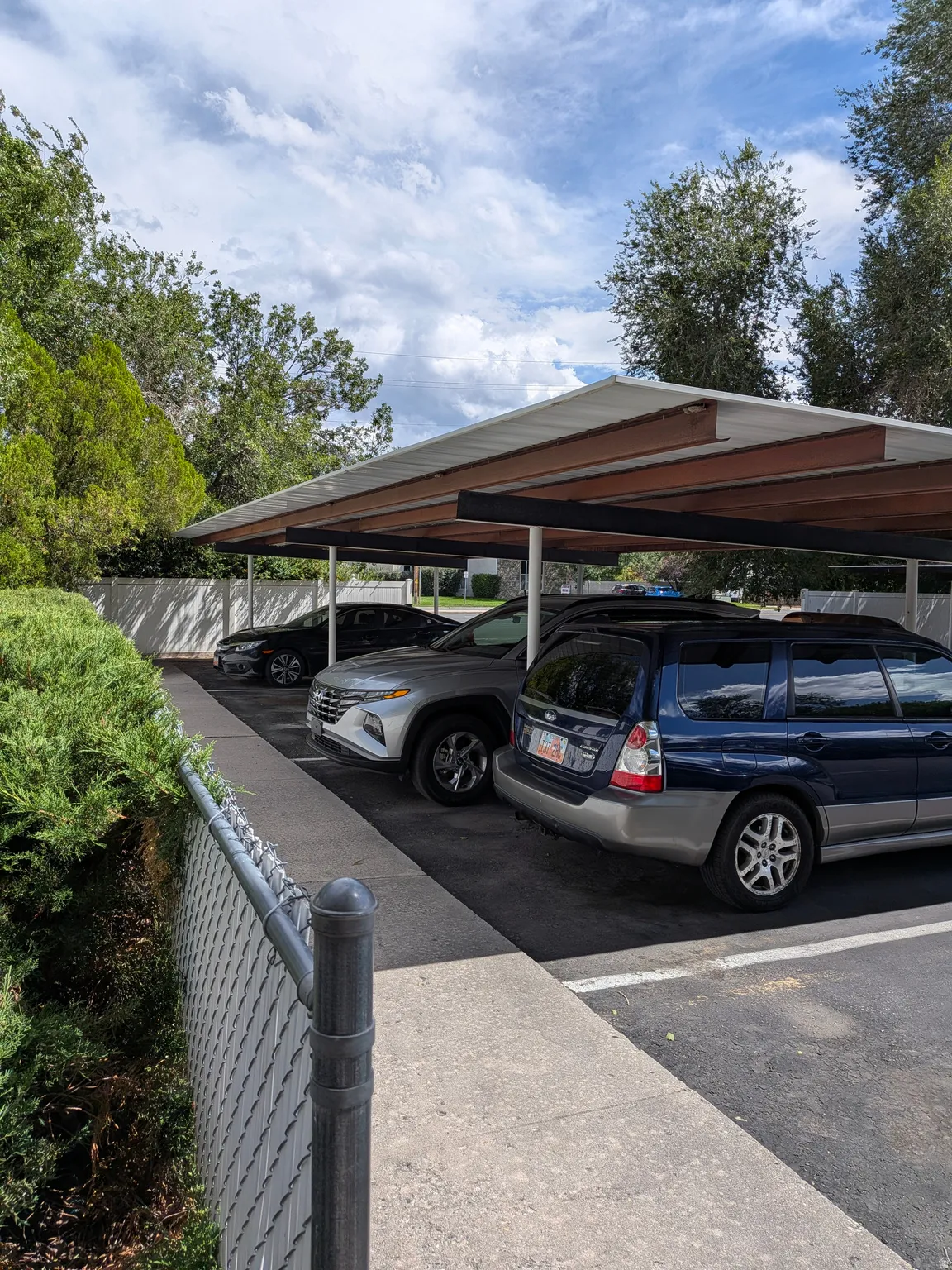 Covered parking structure with multiple spaces, featuring a white roof and exposed structural beams