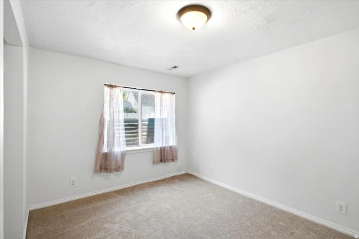 Carpeted flooring, white painted walls, and a single window with blinds