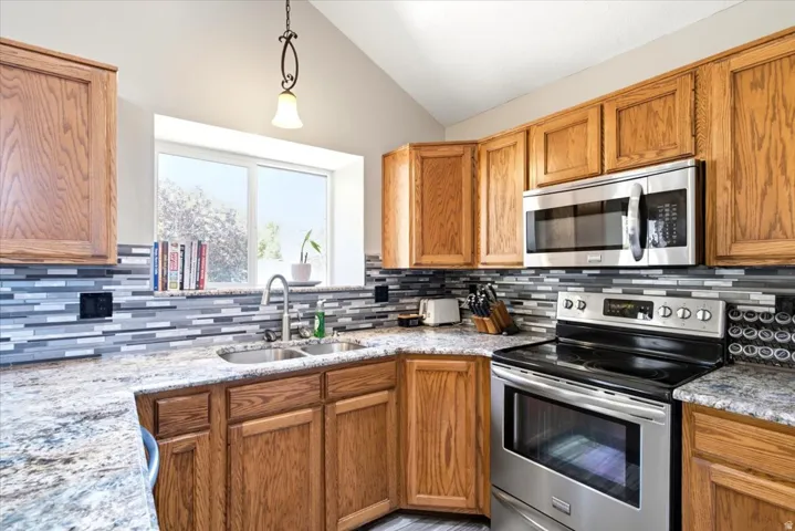 Kitchen featuring wood cabinetry, stainless steel appliances, speckled countertops, and a tiled backsplash