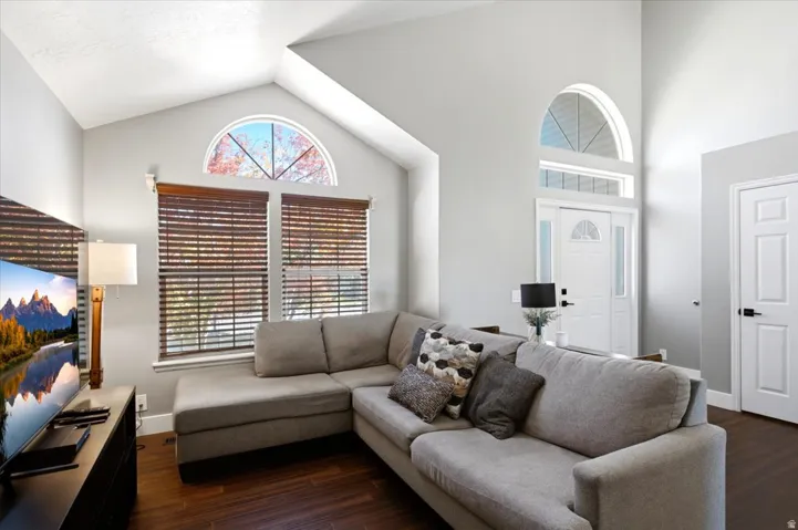 Vaulted ceiling with an arched window, wood-finish flooring, white paneled interior doors, and a front entry door with a transom window