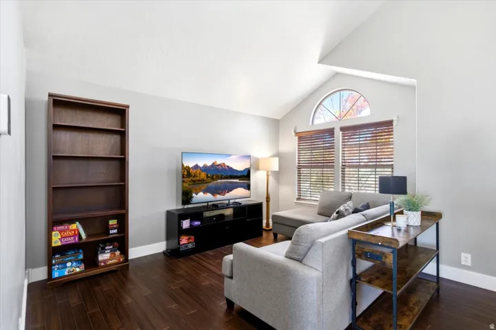 Vaulted ceiling, arched window, wood-finish flooring, built-in media console, wood-slat blinds
