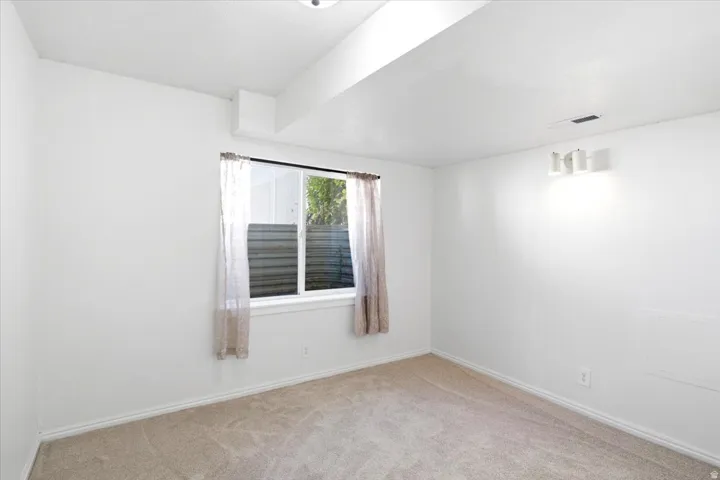 Carpeted room with a window, baseboard trim, and track lighting fixture