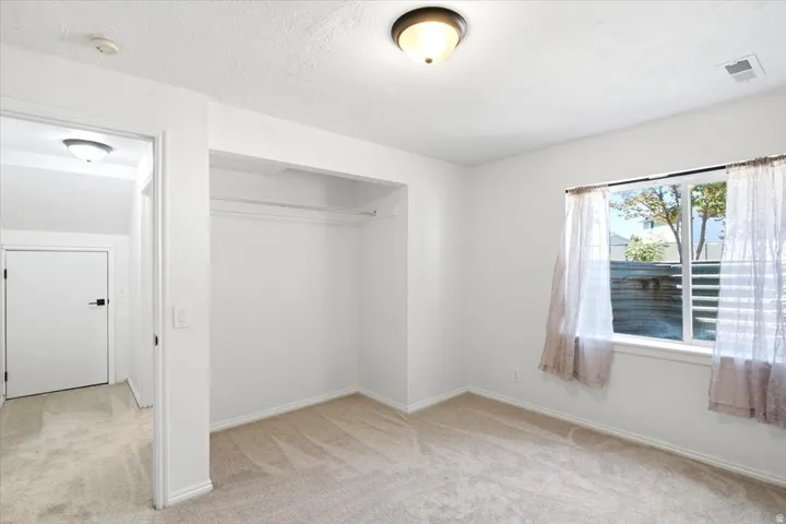 Carpeted room featuring a built-in closet, a window, and ceiling-mounted light fixtures