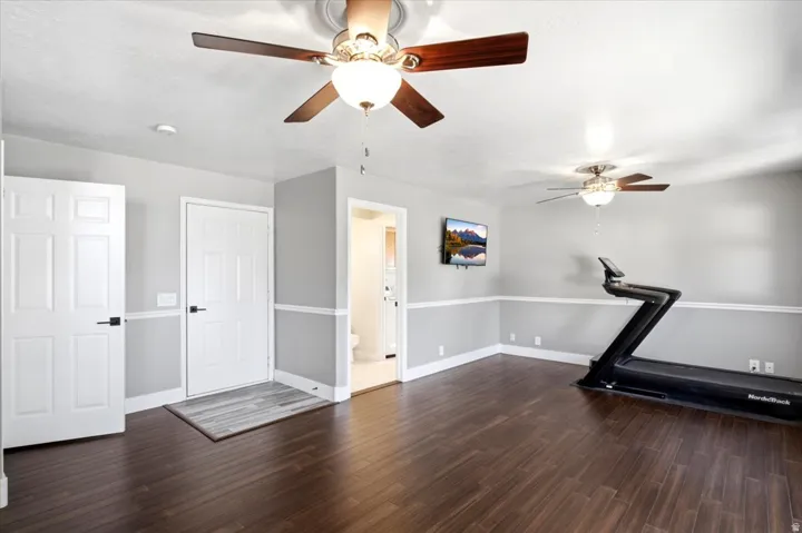 Dark wood-finish flooring, two ceiling fans with light fixtures, and white trim work