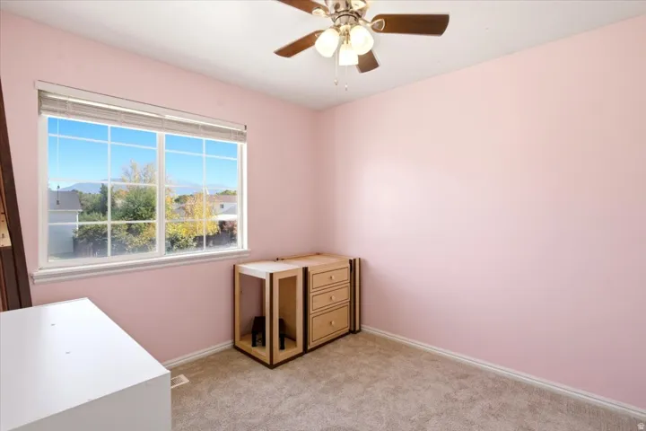 Window with muntins, wall-to-wall carpeting, and a ceiling fan with integrated lighting