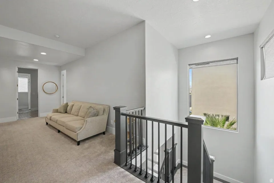 Carpeted landing with recessed lighting, a built-in window, and a dark-finish stair railing