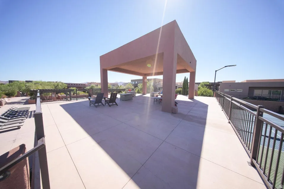 Expansive outdoor patio with a built-in pergola structure, concrete paving, and metal railings