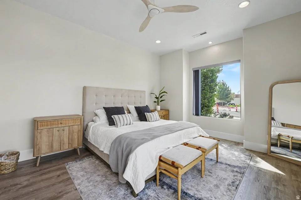 Ceiling fan with wooden blades, recessed ceiling lighting, a large window, and wood-finish flooring