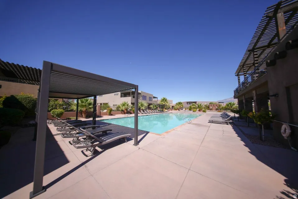 Expansive pool deck featuring a large swimming pool, structured pergolas, and established landscaping