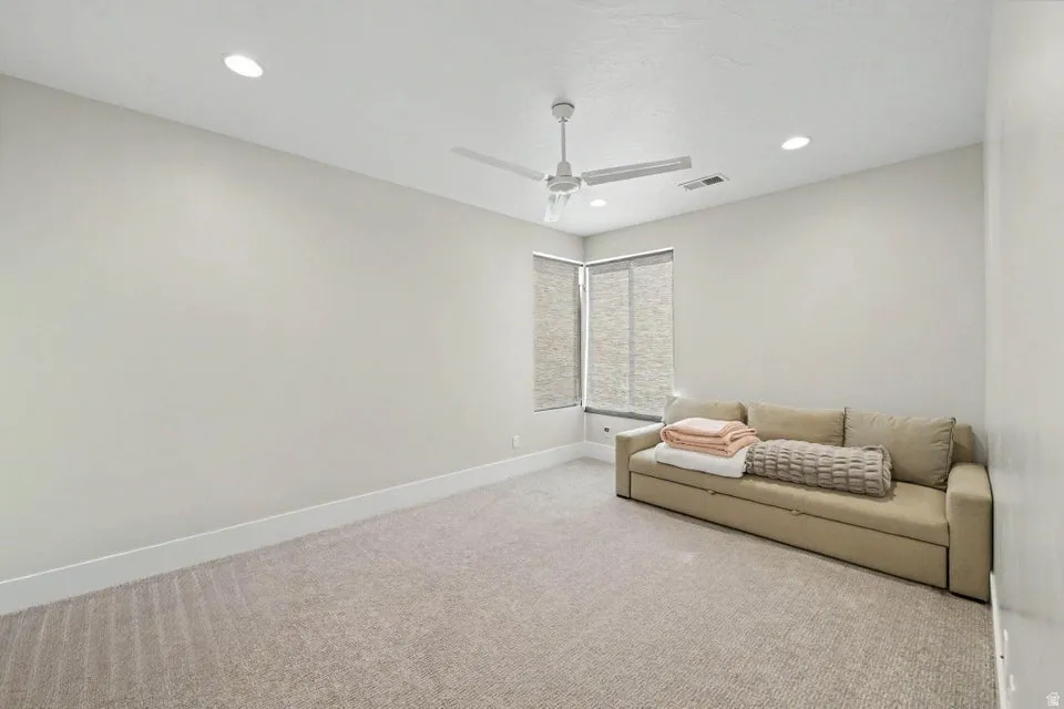 Recessed ceiling lighting, ceiling fan, corner windows with roller shades, and carpeted flooring